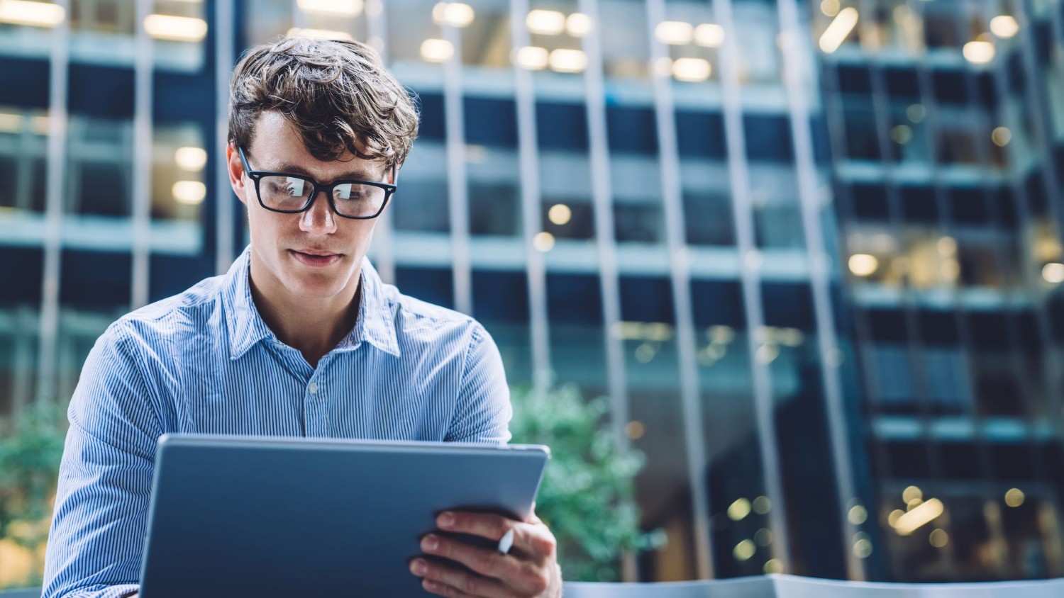 Mann mit Tablet vor einem Bürogebäude