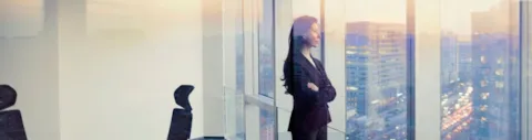 Geschäftsfrau schaut aus einem Bürofenster