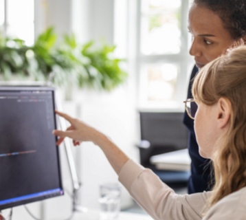 Zwei Frauen schauen gemeinsam auf einen Bildschirm.