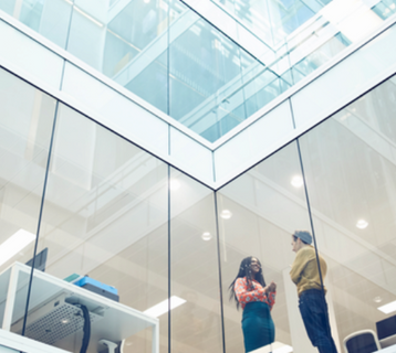Zwei Personen sprechen in einem Büro miteinander.