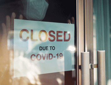 Schild an einer Ladentür, das besagt, dass das Geschäft wegen COVID-19 geschlossen ist.