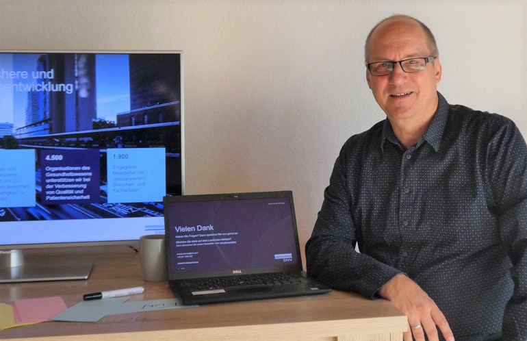 Trainer Stefan Mayer am Schreibtisch mit Laptop und Bildschirm